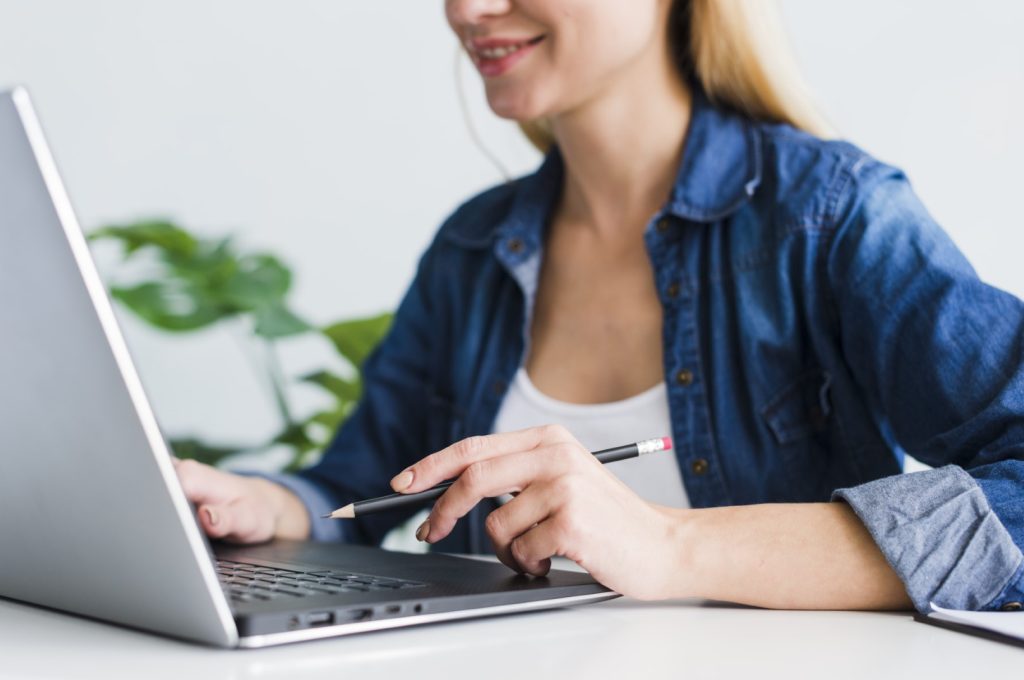 hembra-joven-sonriente-que-usa-ordenador-portatil-lugar-trabajo